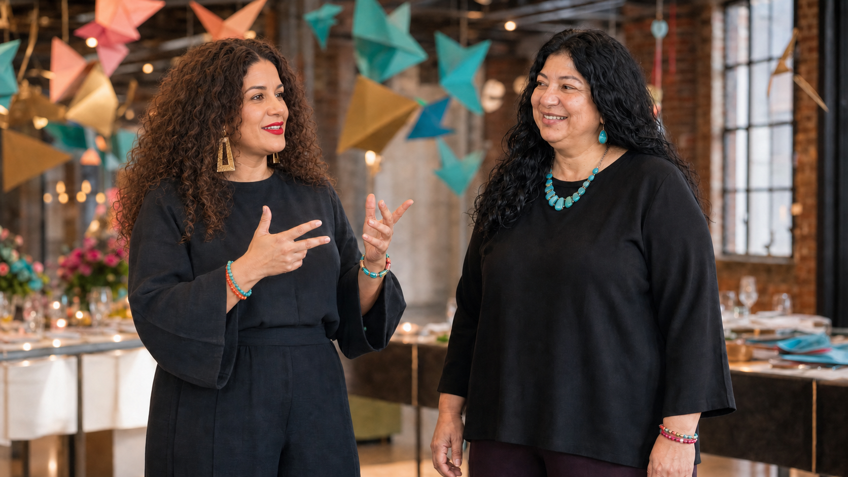 Matanah founders Shelly and Sofia presenting in a decorated event space with colorful origami installations